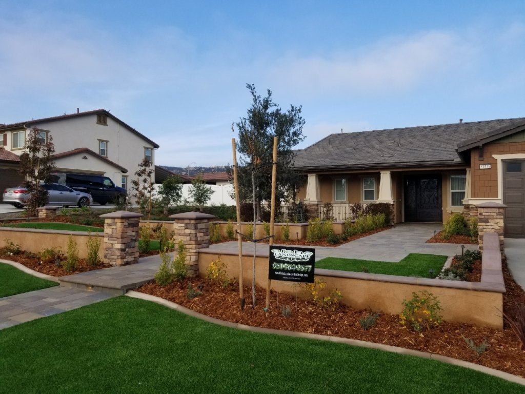 Front yard with turf, stucco planter walls, and paver walkway
