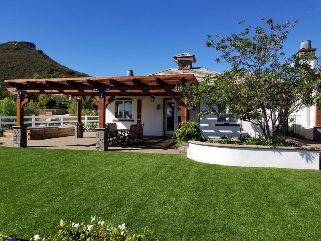 Pergola over paver patio beside a turf lawn